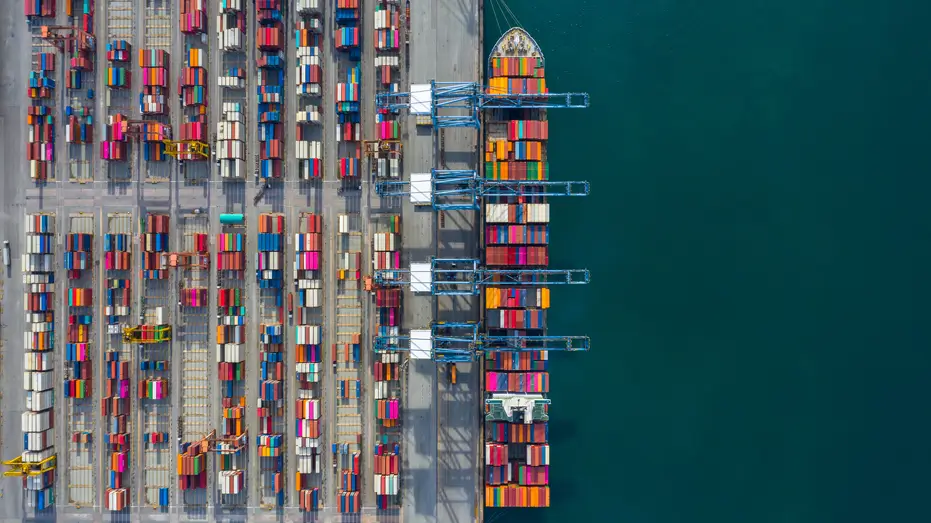 Aerial view of cargo containers and ship at port, symbolising global trade and customs tariffs