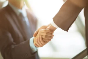 Two business professionals shaking hands symbolising cross-border legal and financial cooperation