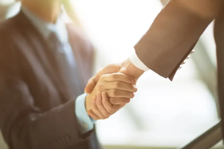 Two business professionals shaking hands symbolising cross-border legal and financial cooperation