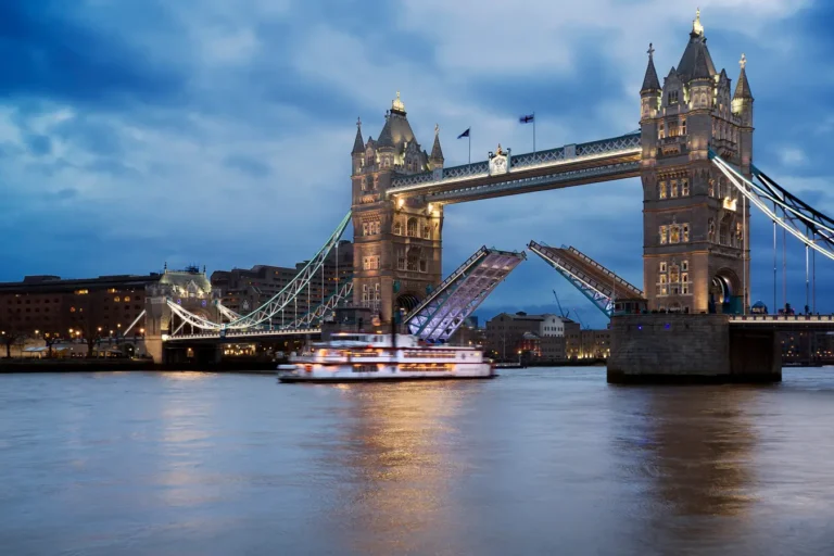 Tower Bridge in London at dusk with the bridge opening over the River Thames, symbolising UK financial markets.